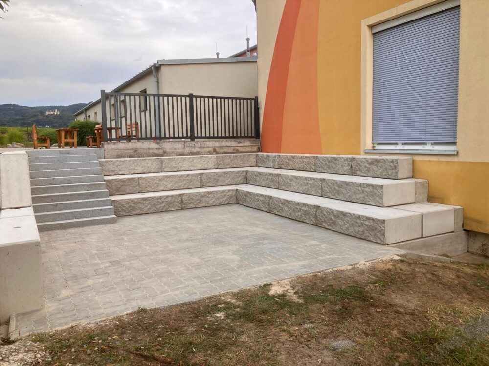 Betonstufen und Sitzgelegenheit vor einem Haus mit gelber Fassade, Österreich