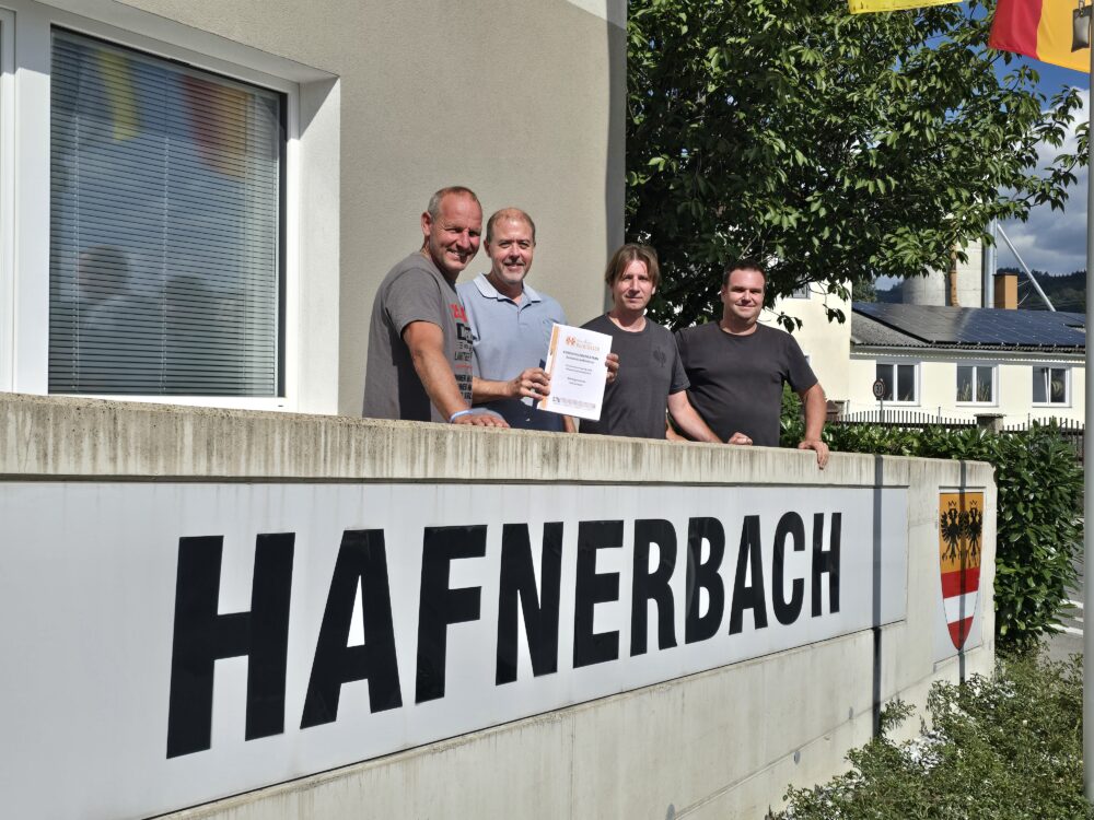 Vier Männer mit Urkunde vor dem Schild Hafnerbach
